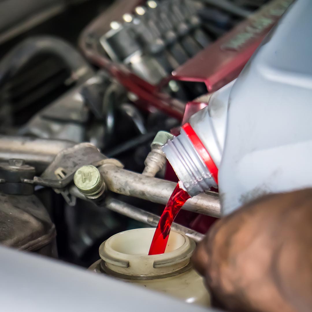 Person pouring transmission fluid into an engine